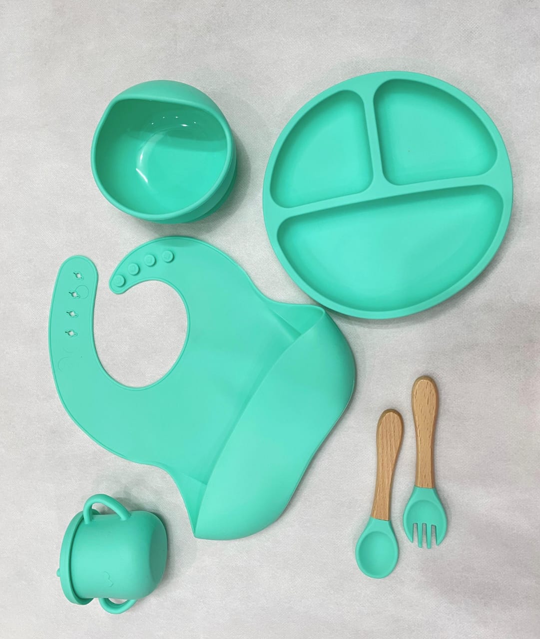 A top-down view of a pink silicone baby suction plate filled with healthy toddler snacks on a clean high-chair tray.