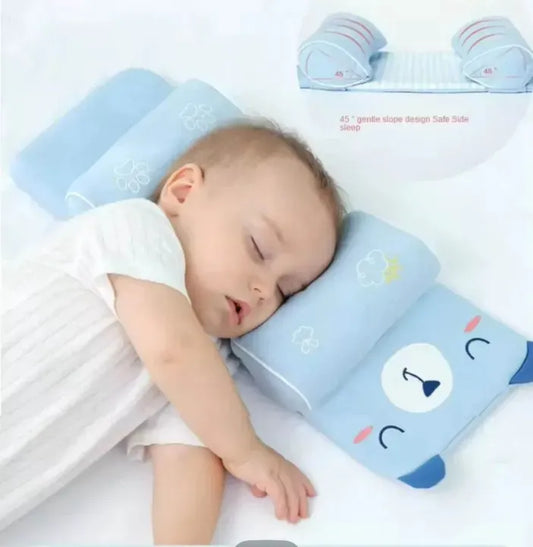A newborn infant sleeping peacefully on a blue ergonomic baby head shaping pillow to prevent flat head syndrome in a crib.