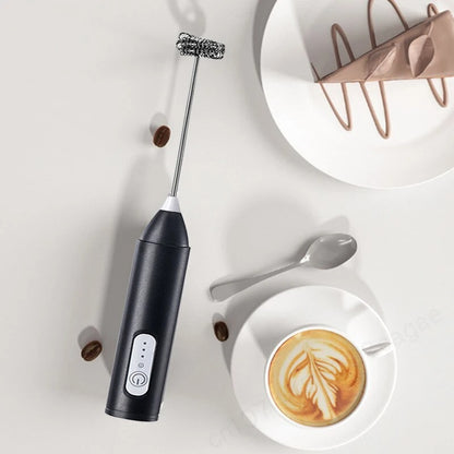Close-up of a handheld electric milk frother whisking milk into a rich, creamy foam in a clear glass mug.