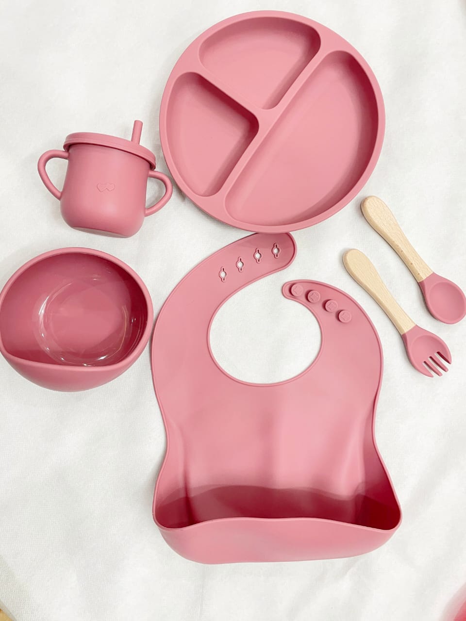 A top-down view of a pink silicone baby suction plate filled with healthy toddler snacks on a clean high-chair tray.