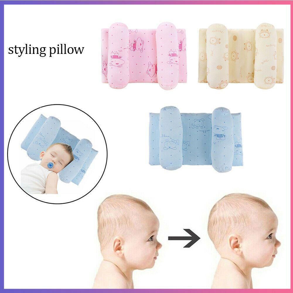 A newborn infant sleeping peacefully on a blue ergonomic baby head shaping pillow to prevent flat head syndrome in a crib.