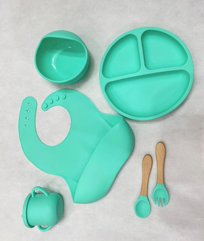 A top-down view of a pink silicone baby suction plate filled with healthy toddler snacks on a clean high-chair tray.